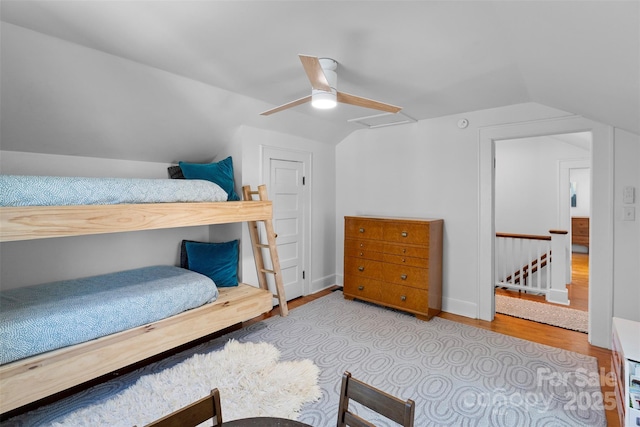 bedroom with a ceiling fan, lofted ceiling, wood finished floors, and baseboards