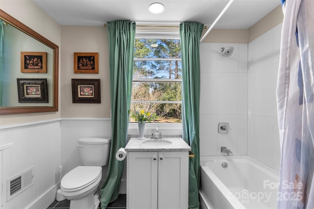 bathroom featuring visible vents, toilet, wainscoting, shower / bath combination with curtain, and vanity