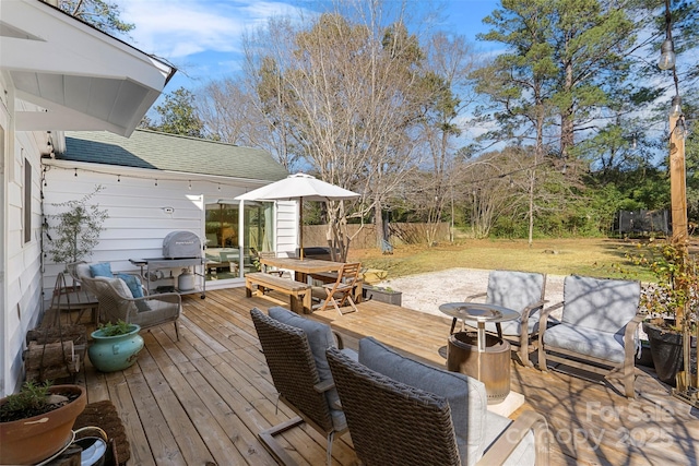 deck with outdoor dining space, grilling area, and fence