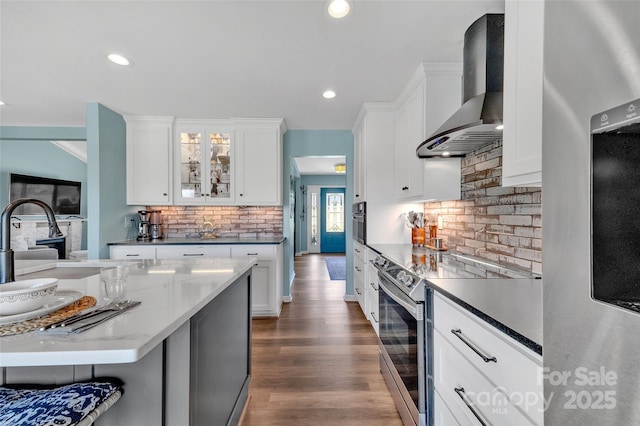 kitchen with dark wood-style floors, white cabinetry, recessed lighting, stainless steel appliances, and wall chimney range hood