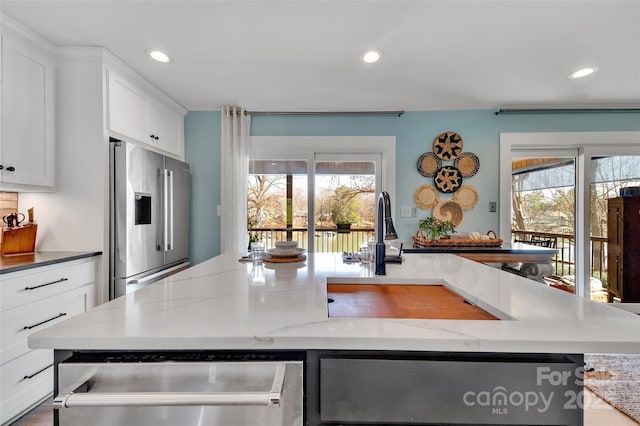 kitchen featuring a sink, light stone counters, appliances with stainless steel finishes, and recessed lighting