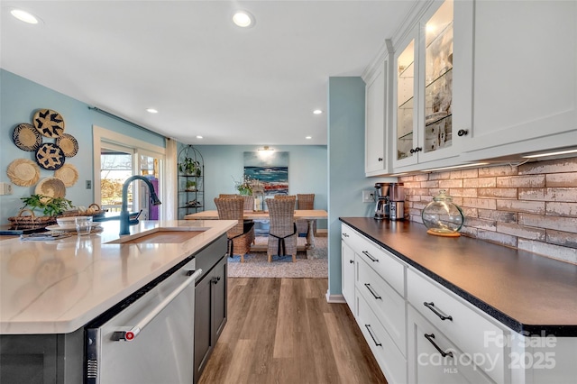 kitchen with a sink, recessed lighting, decorative backsplash, dishwasher, and dark wood-style flooring