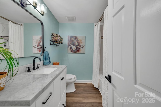 bathroom featuring visible vents, toilet, wood finished floors, baseboards, and vanity