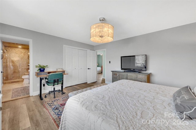 bedroom featuring ensuite bath, wood finished floors, baseboards, and a closet