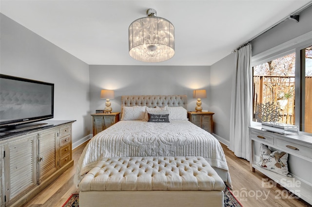 bedroom featuring light wood-type flooring, baseboards, and a chandelier