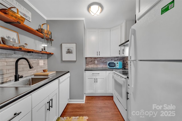 kitchen featuring dark countertops, open shelves, white appliances, white cabinetry, and a sink