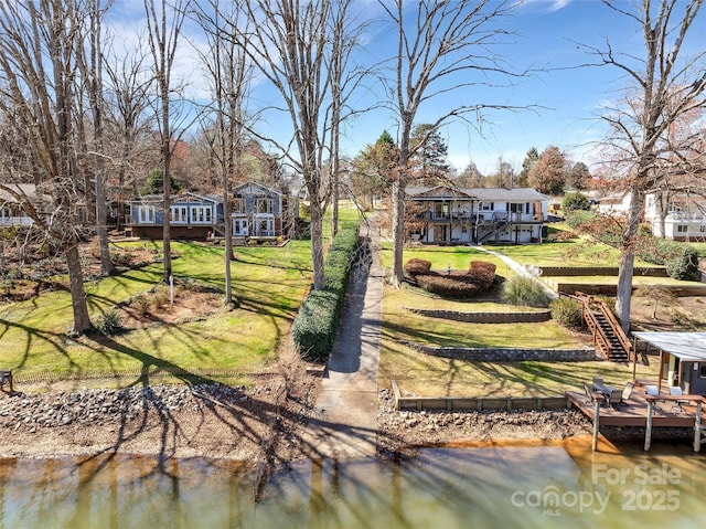 back of property featuring a deck with water view, stairs, and a yard