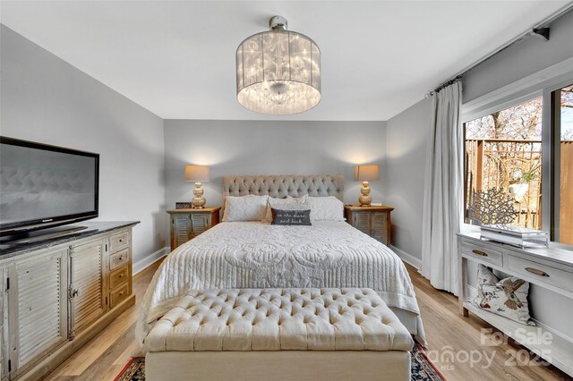 bedroom with baseboards, an inviting chandelier, and light wood finished floors