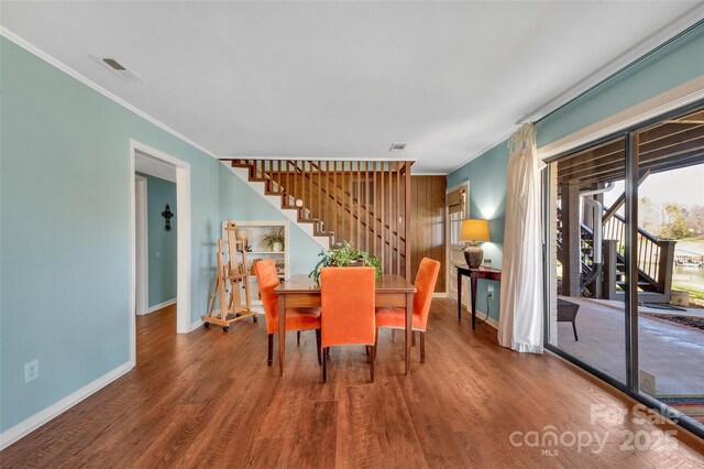 dining room with visible vents, ornamental molding, stairs, and wood finished floors