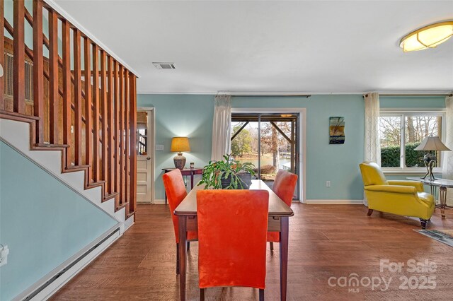 dining room with a wealth of natural light, wood finished floors, visible vents, and baseboard heating