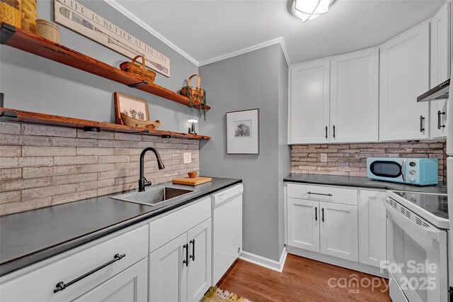 kitchen featuring dark countertops, a sink, white appliances, and open shelves