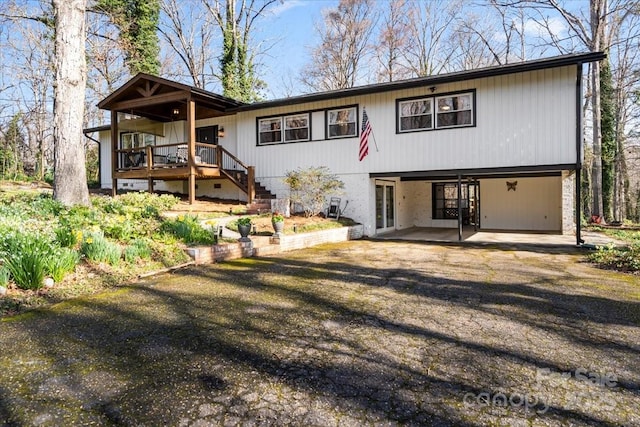 rear view of property featuring stairs, a carport, and dirt driveway