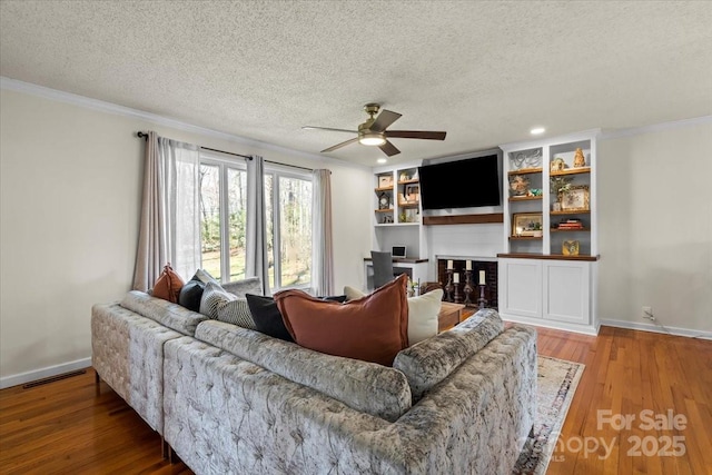 living room with visible vents, a textured ceiling, wood finished floors, and crown molding