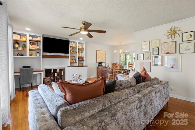 living area featuring built in study area, a textured ceiling, ornamental molding, and wood-type flooring