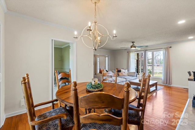 dining space with light wood-type flooring, baseboards, ornamental molding, and ceiling fan with notable chandelier