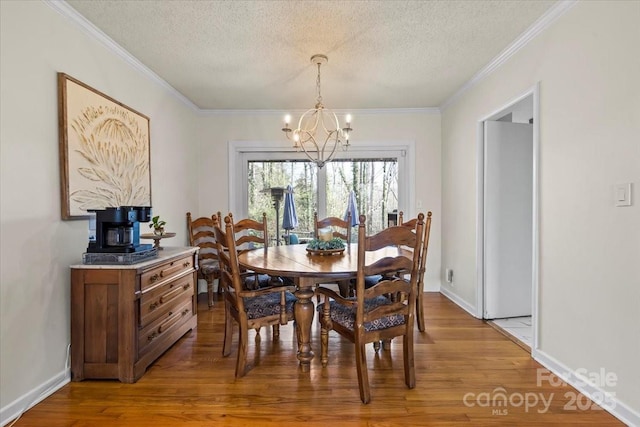 dining area with light wood-type flooring, a notable chandelier, ornamental molding, and a textured ceiling