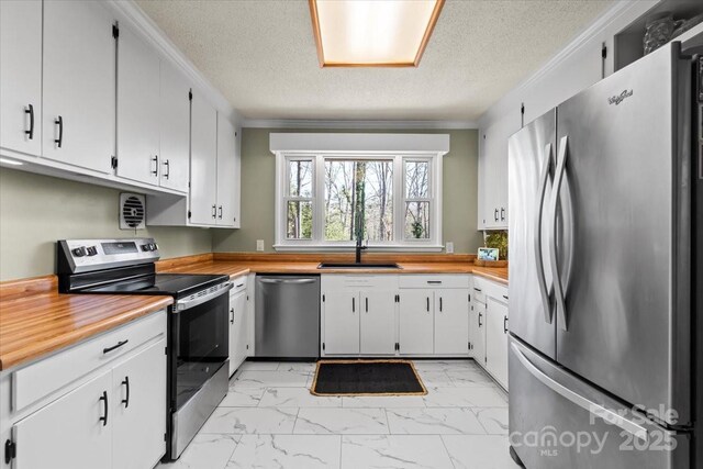 kitchen with crown molding, marble finish floor, appliances with stainless steel finishes, and a sink