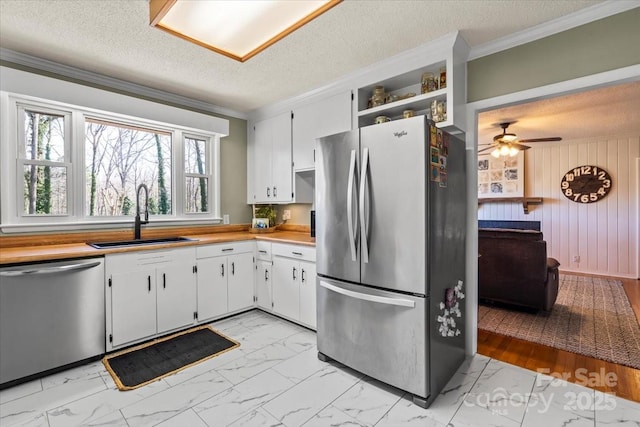 kitchen featuring marble finish floor, ornamental molding, a sink, stainless steel appliances, and light countertops