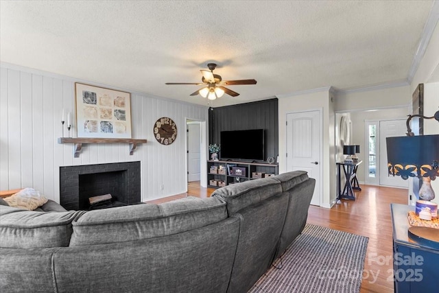 living area featuring wood finished floors, crown molding, a fireplace, and a textured ceiling