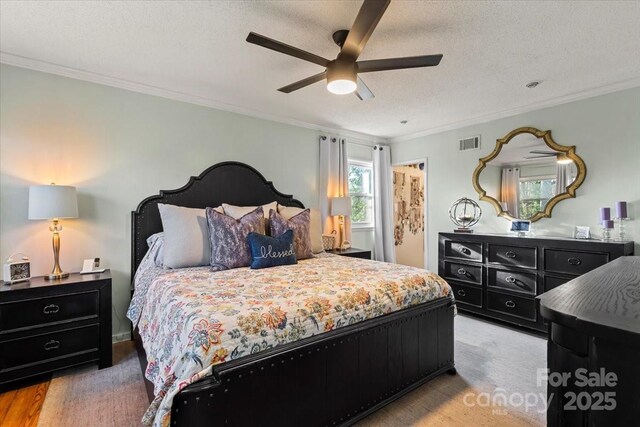 bedroom featuring visible vents, a textured ceiling, crown molding, and ceiling fan