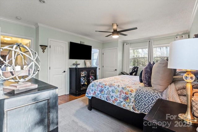 bedroom featuring ceiling fan, wood finished floors, and crown molding