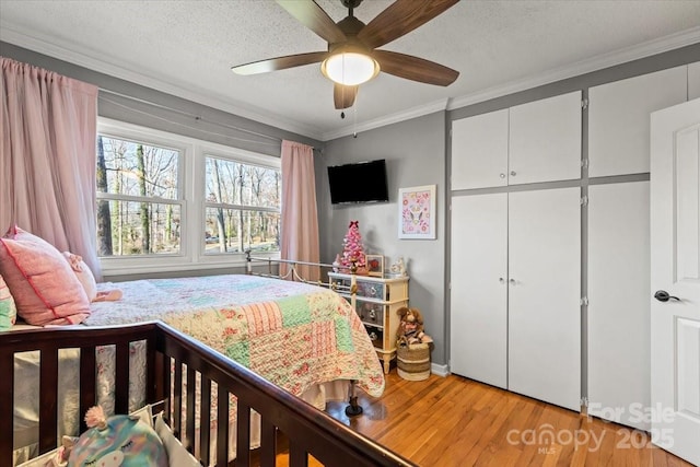 bedroom with a ceiling fan, light wood-style floors, crown molding, and a textured ceiling