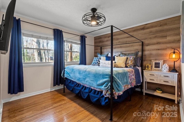 bedroom with a textured ceiling, wood finished floors, and ornamental molding