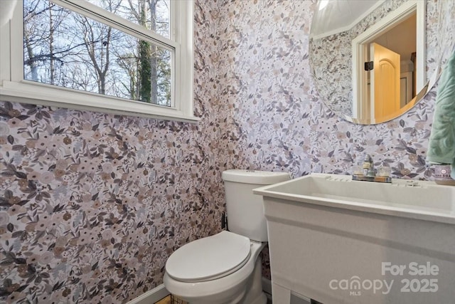 half bath featuring toilet, wallpapered walls, and vanity