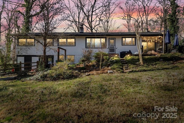 view of front of home featuring a front lawn, fence, and a chimney