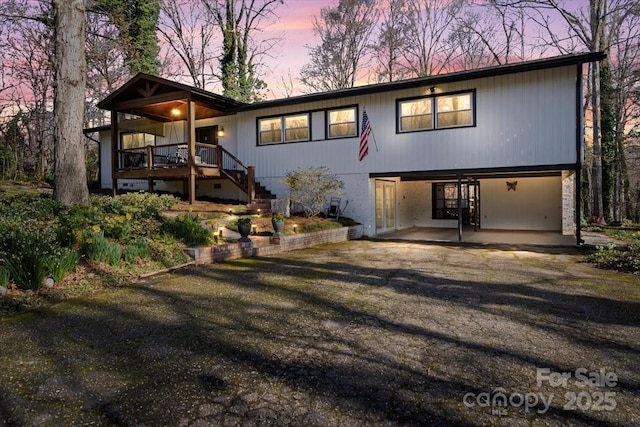 back of house at dusk featuring stairway and dirt driveway