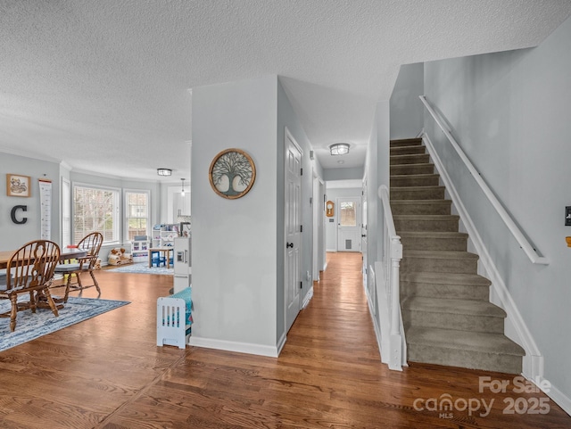 interior space featuring stairs, wood finished floors, baseboards, and a textured ceiling