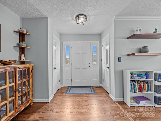 entrance foyer with a textured ceiling, baseboards, and wood finished floors