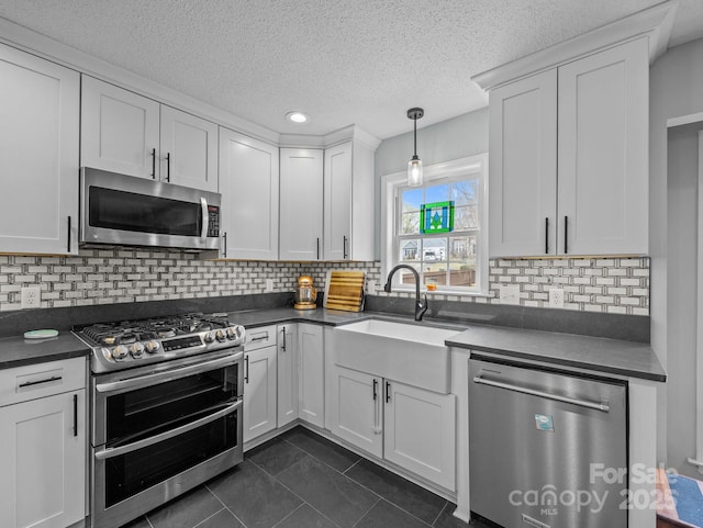 kitchen featuring white cabinetry, dark countertops, appliances with stainless steel finishes, and a sink