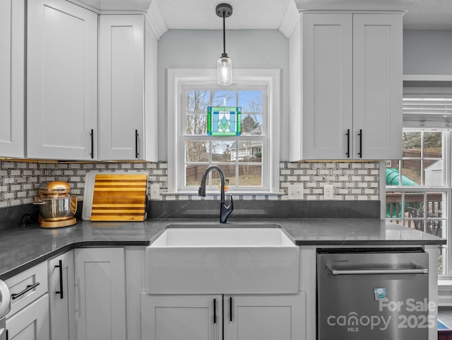 kitchen featuring a sink, decorative backsplash, dishwasher, dark countertops, and a wealth of natural light