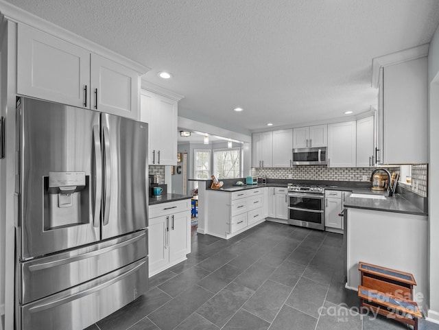 kitchen featuring a sink, dark countertops, white cabinets, and stainless steel appliances