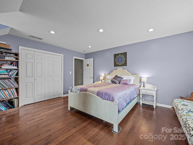 bedroom featuring a closet, visible vents, a textured ceiling, and wood-type flooring