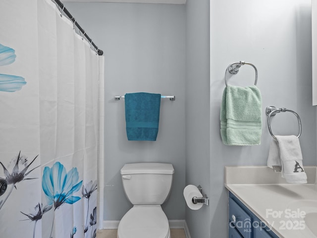 bathroom with curtained shower, toilet, vanity, and baseboards