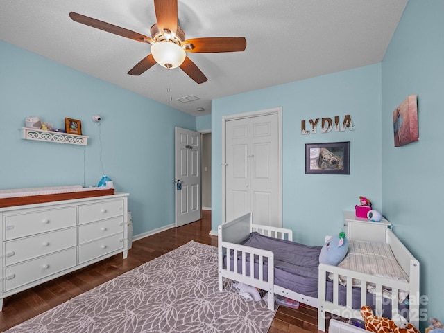 bedroom featuring visible vents, a ceiling fan, wood finished floors, a closet, and baseboards