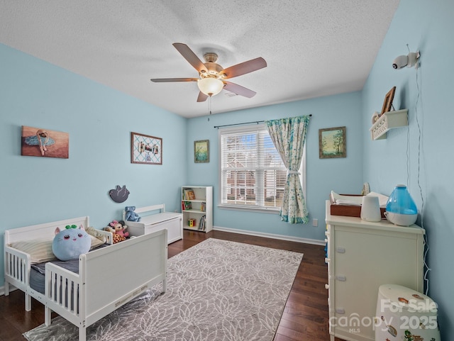 bedroom with a ceiling fan, dark wood-style floors, baseboards, and a textured ceiling