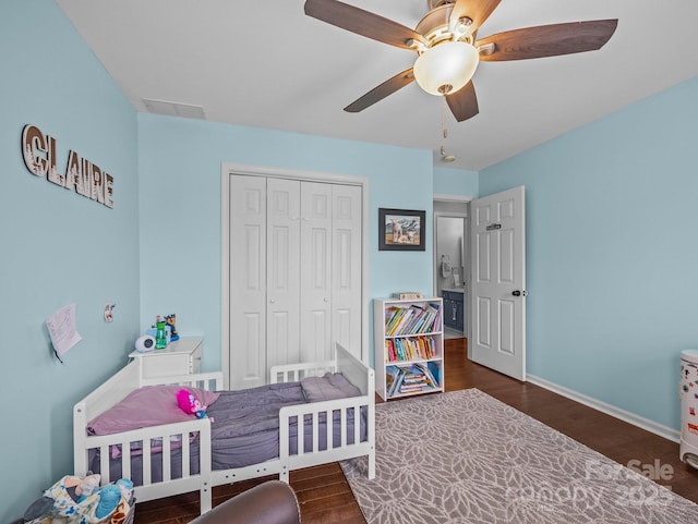 bedroom with wood finished floors, visible vents, a closet, and baseboards