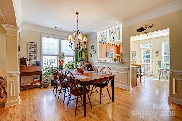 dining area featuring crown molding, decorative columns, visible vents, and light wood-type flooring