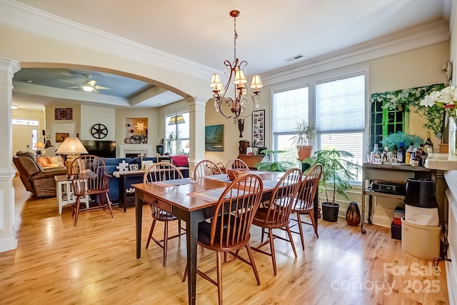 dining area featuring light wood-style floors, decorative columns, a fireplace, and visible vents