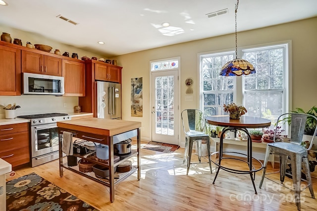 kitchen with light wood finished floors, visible vents, stainless steel appliances, and light countertops