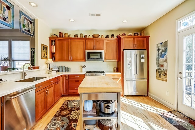 kitchen with visible vents, open shelves, a sink, stainless steel appliances, and light wood-style floors