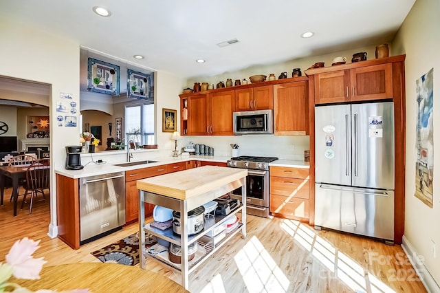 kitchen with visible vents, light wood-style flooring, a sink, appliances with stainless steel finishes, and light countertops