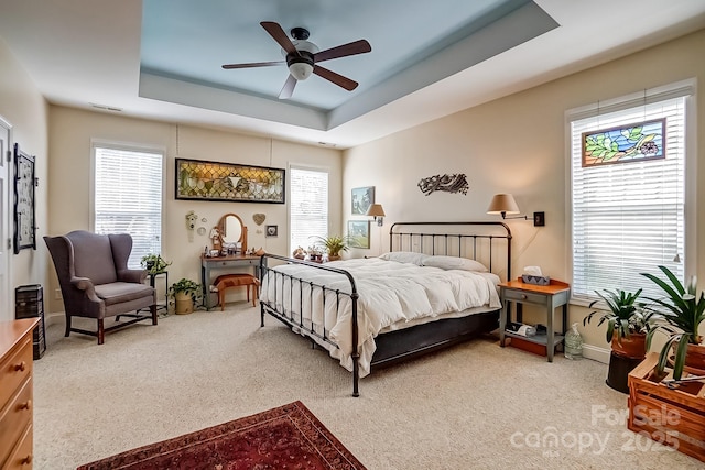 bedroom featuring visible vents, ceiling fan, baseboards, carpet, and a tray ceiling