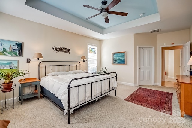 bedroom featuring a raised ceiling, carpet, visible vents, and baseboards