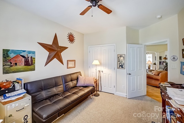 living room with ceiling fan, baseboards, and light carpet