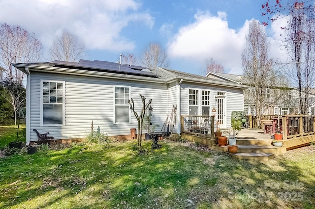 back of property featuring solar panels, a yard, and a wooden deck