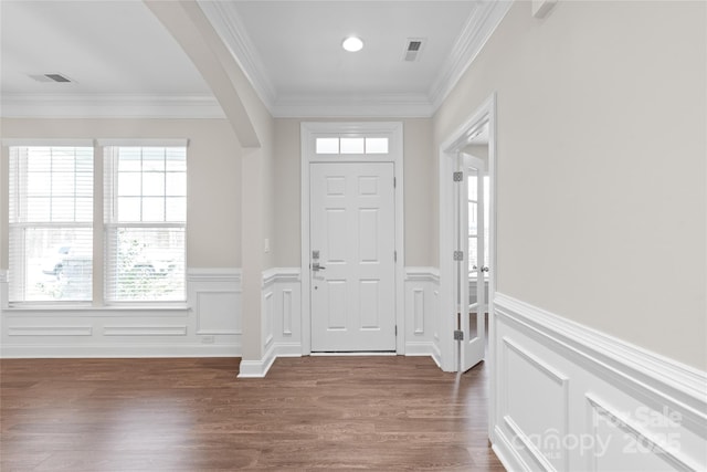 foyer featuring crown molding, arched walkways, visible vents, and dark wood-style flooring